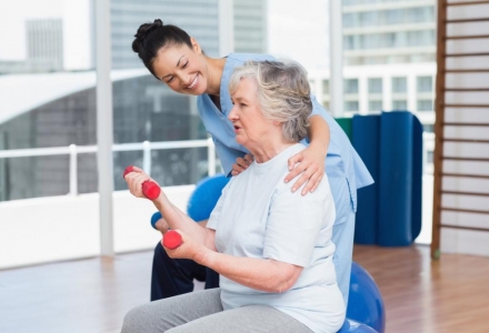 trainer-looking-at-senior-woman-lifting-dumbbells